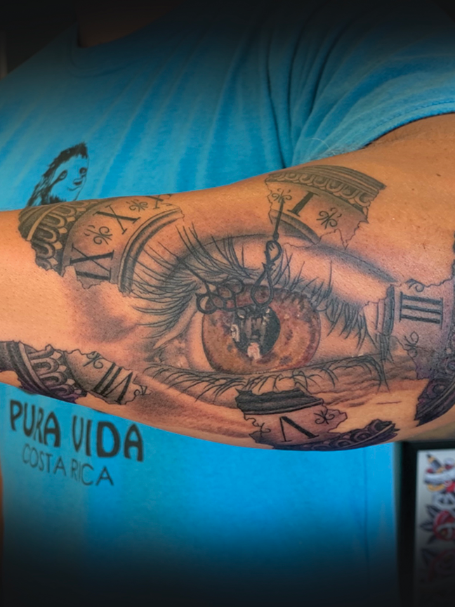 Clock and eyeball tattoo on arm
