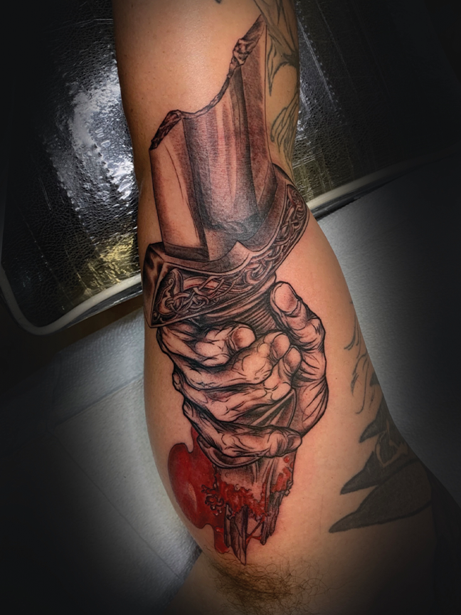 Hand holding broken sword tattoo