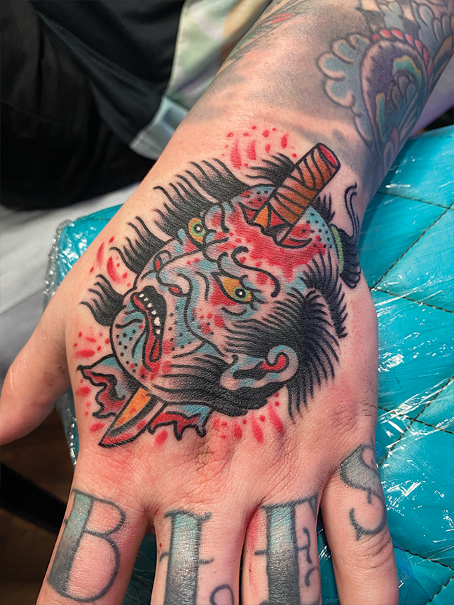 face and sword tattoo on hand