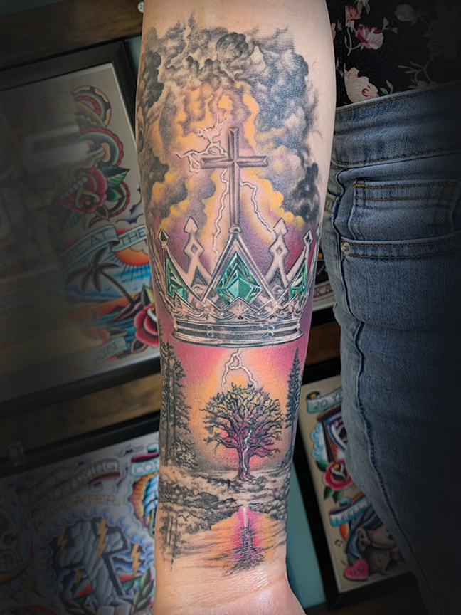 A cross, Crown and tree tattoo on arm
