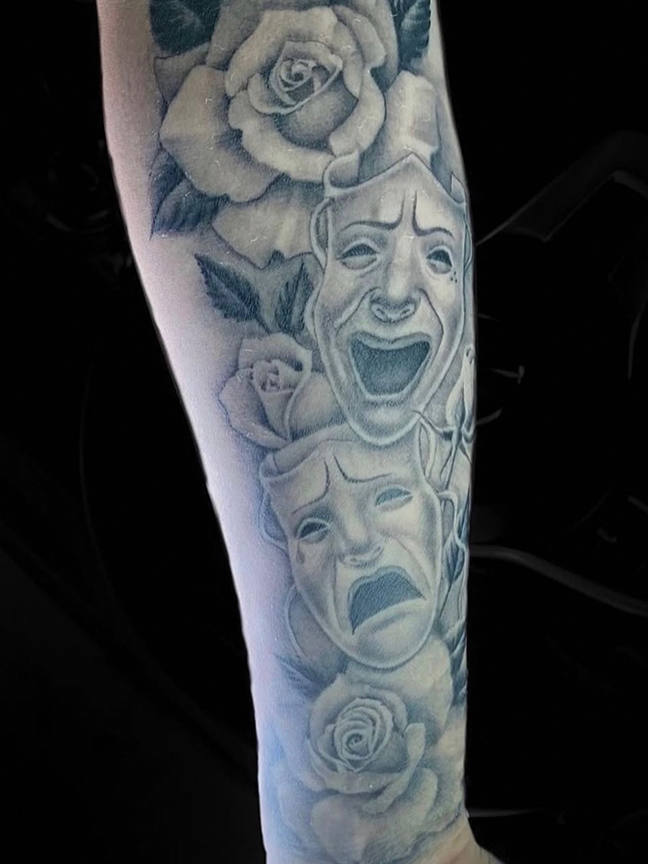 laughing masks tattoo on arm
